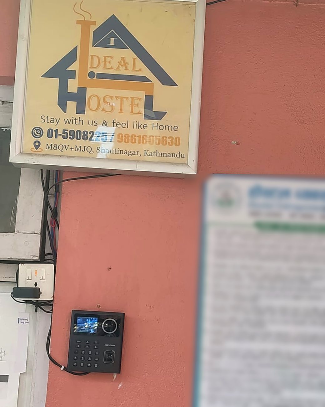 Ideal Hostel's sign above the Hikvision face terminal at its gate